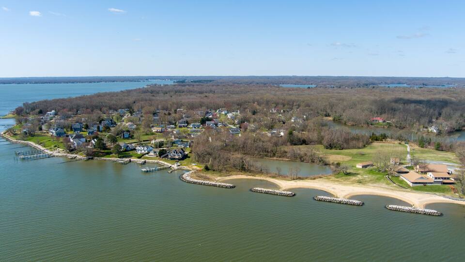 An aerial view of a lakeside community with houses, docks, and a bridge.