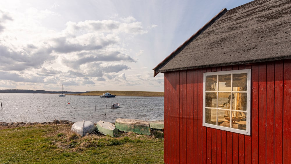 a red hut on the shore an some boats at Jyllinge, Denmark, Marts 29, 2022