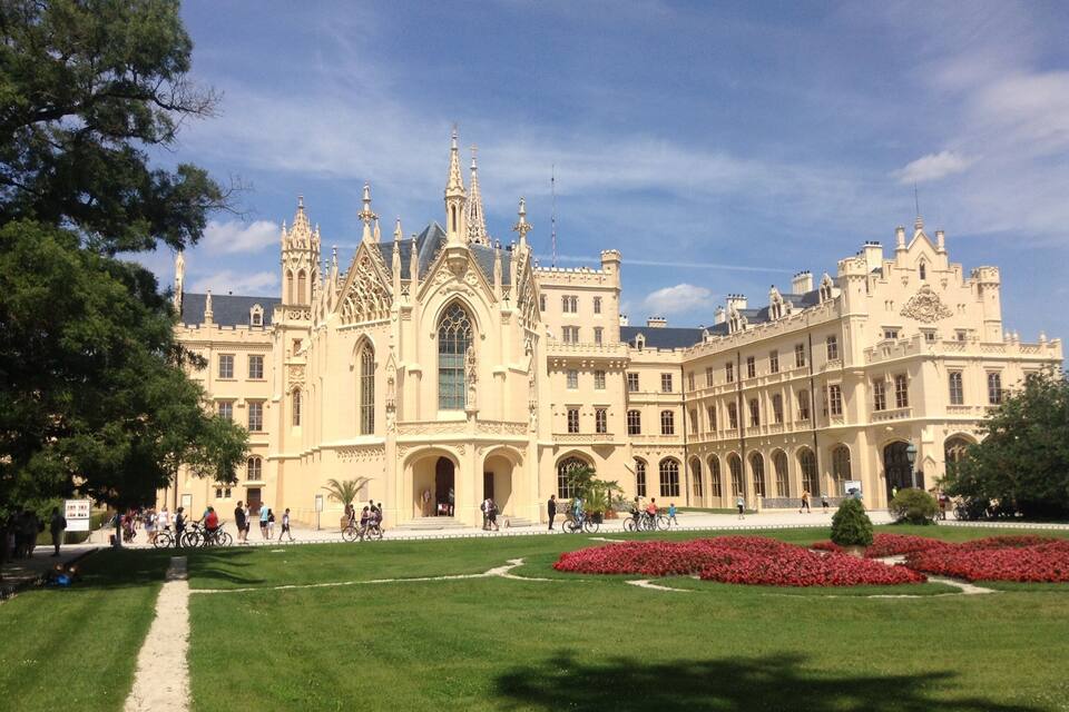 A grand, ornate building with intricate architecture and a well-maintained garden.
