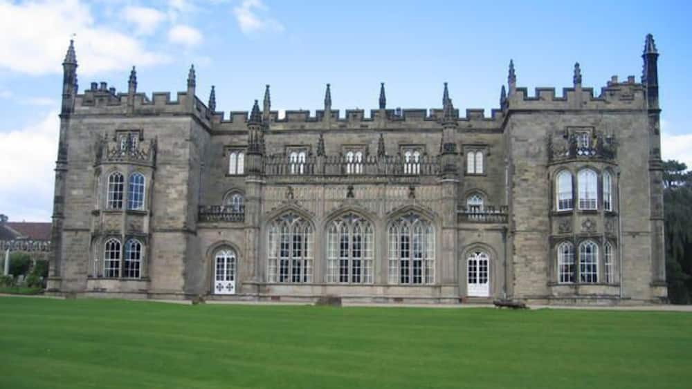 A large, historic stone building with multiple towers and arched windows.