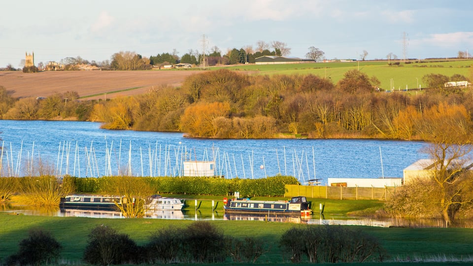 A river with boats, a church, and a field.
