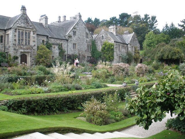A historic stone building with a well-manicured garden and a stone staircase.