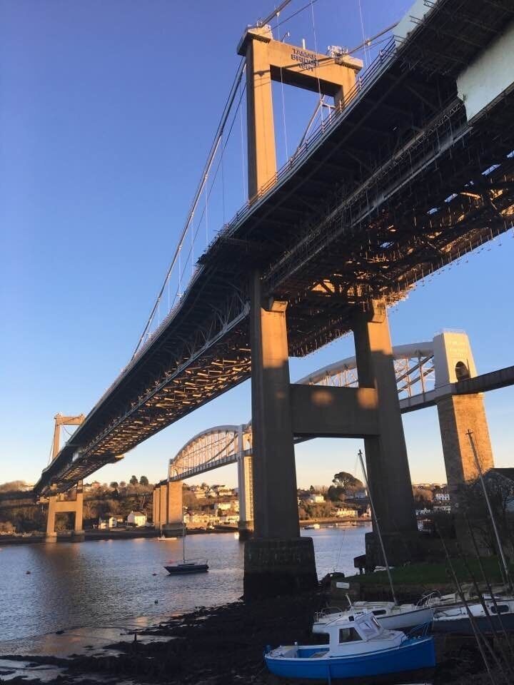 A large suspension bridge over a river with boats docked nearby.