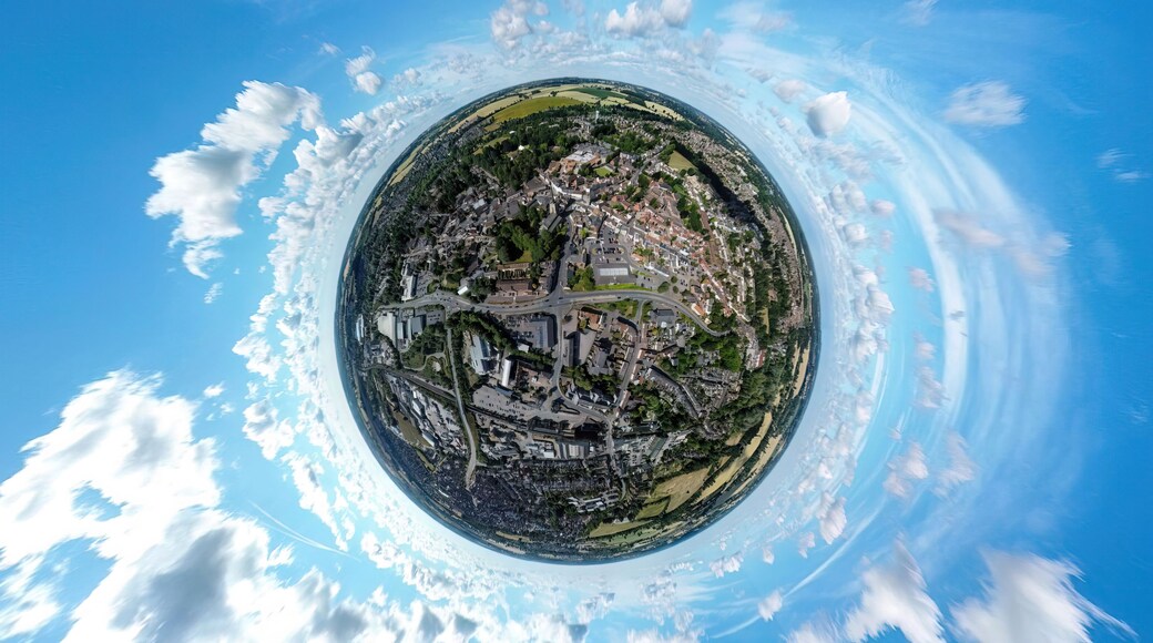 A panoramic view of a town with a prominent church, a roundabout, and surrounding greenery.