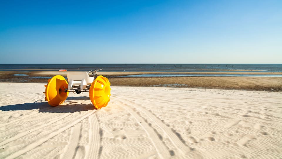 A sandy beach with a vehicle and a clear blue sky.