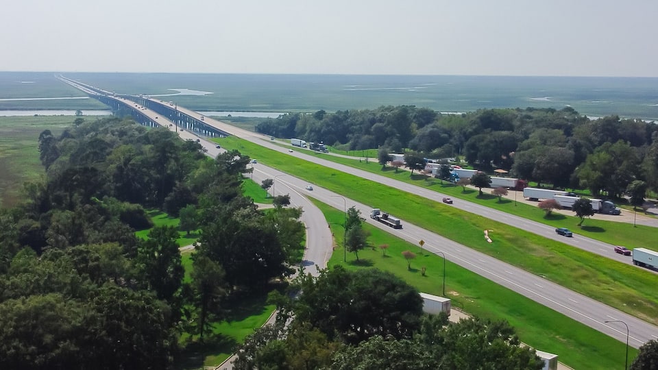 A highway with a bridge over water, surrounded by greenery and trees.