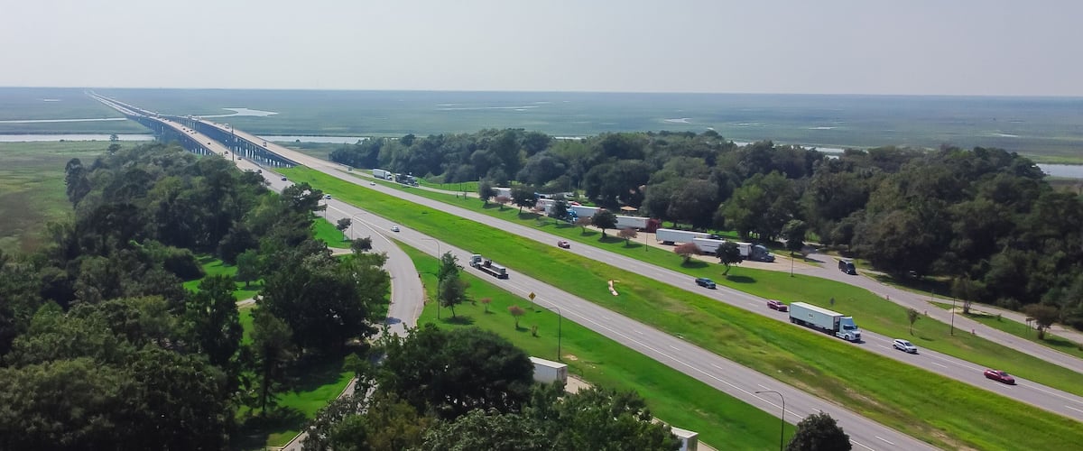 A highway with a bridge over water, surrounded by greenery and trees.