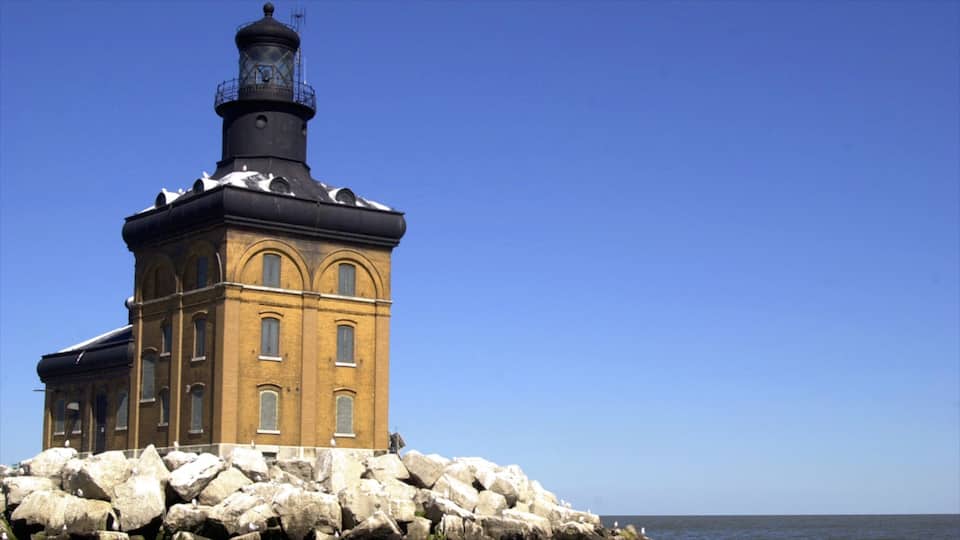 A lighthouse on a rocky outcrop with a clear blue sky.