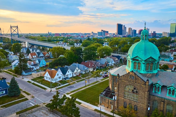 A cityscape with a prominent church with a turquoise dome, a large bridge, and modern buildings in the background.