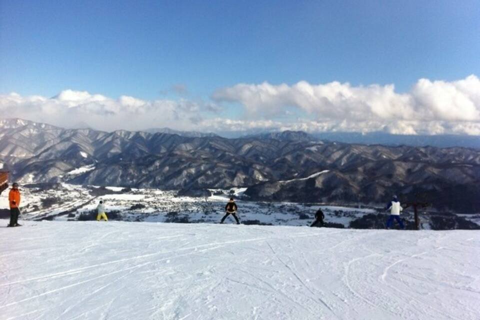 A snowy mountain landscape with skiers and snowboarders.