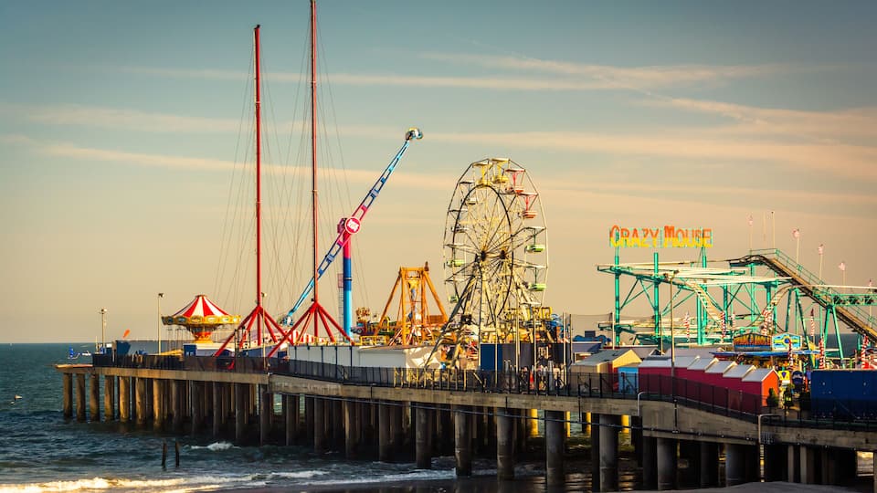 A pier with a Ferris wheel, a crane, and a sign that reads "Crazy Mouse."