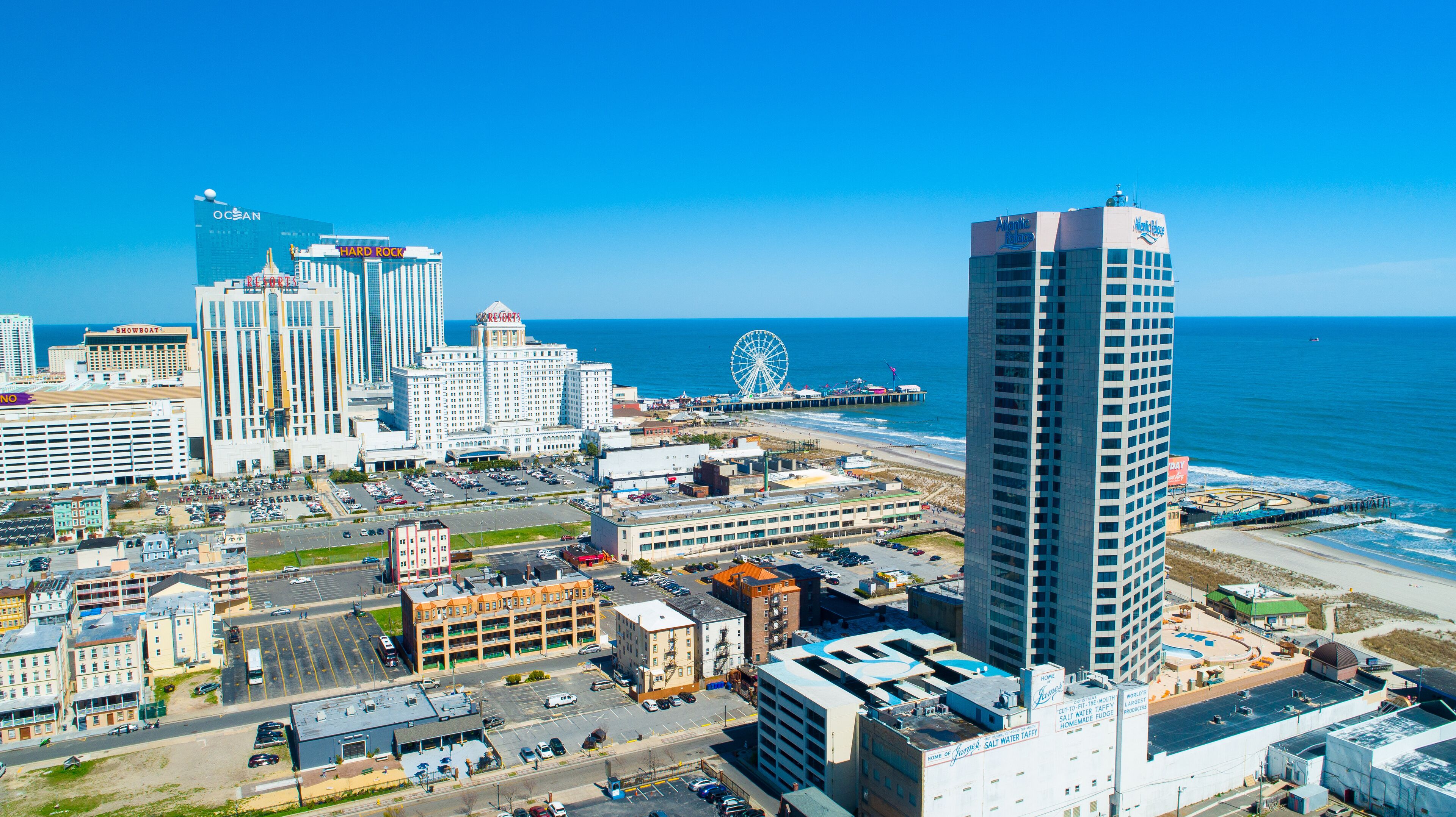 A coastal cityscape with a prominent Ferris wheel, high-rise buildings, and a beach.