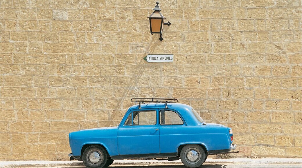 Blue Car Parked in Front of a Brick Wall Under a Road Name Sign, Xaghra, Gozo, Malta