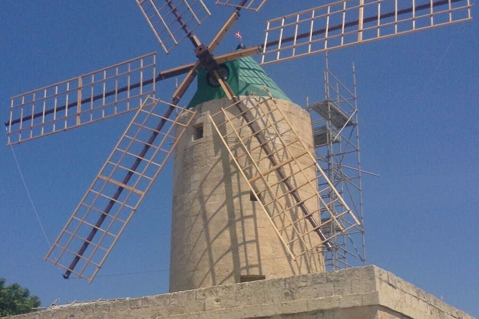 A windmill with a green top and a metal lattice structure.
