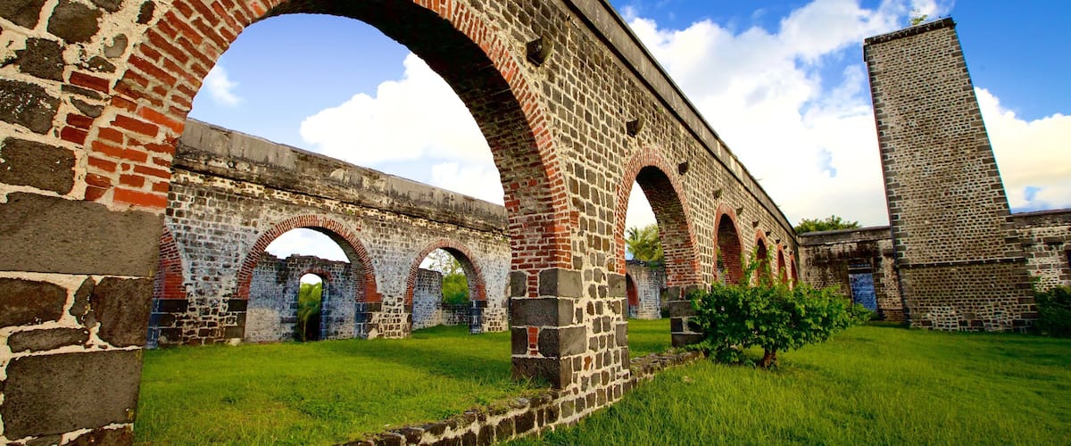 A stone bridge with arches, a grassy area, and a tall brick structure.