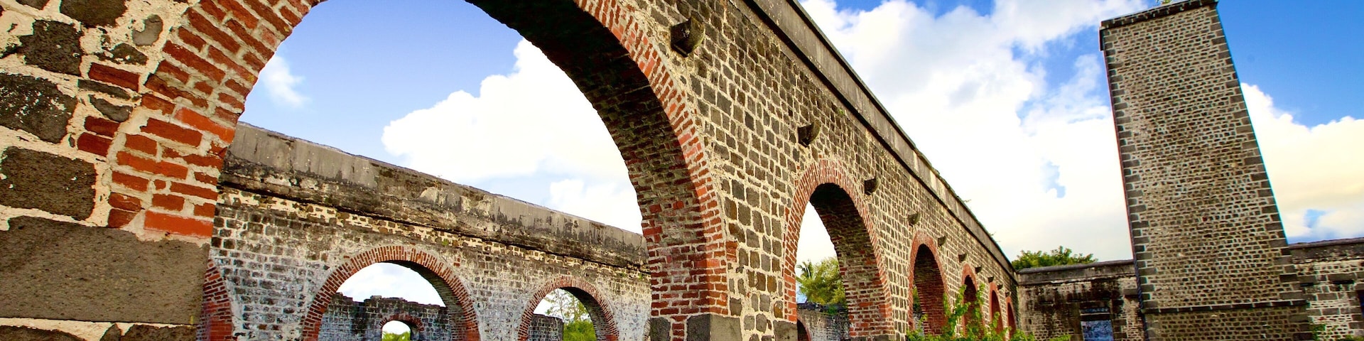 A stone bridge with arches, a grassy area, and a tall brick structure.