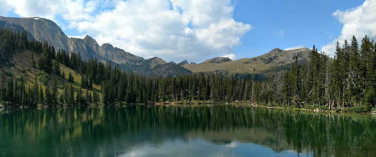 A mountain lake surrounded by dense forests and rugged mountains.