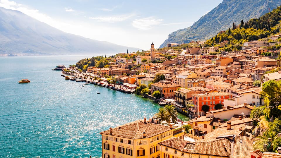 A coastal town with a river, buildings, and mountains in the background.