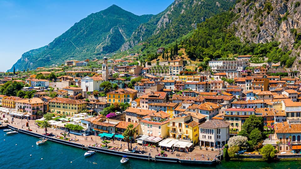 A coastal town with colorful buildings, a marina, and mountains in the background.