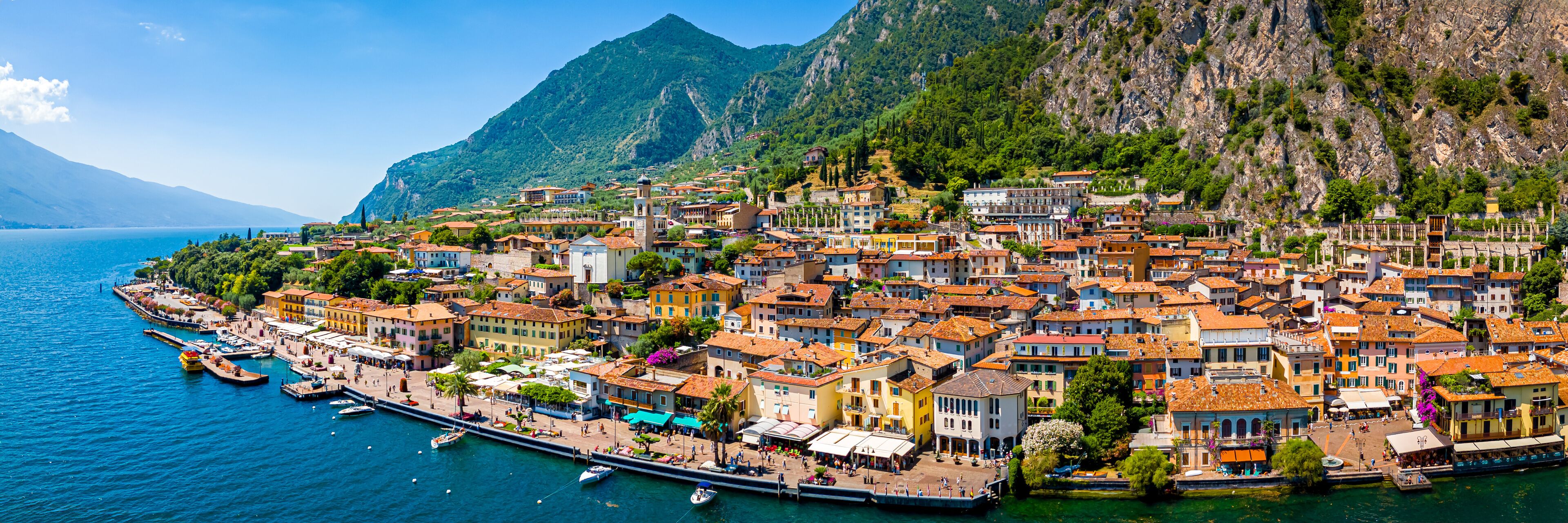 A coastal town with colorful buildings, a marina, and mountains in the background.