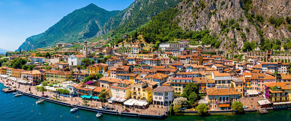 A coastal town with colorful buildings, a marina, and mountains in the background.