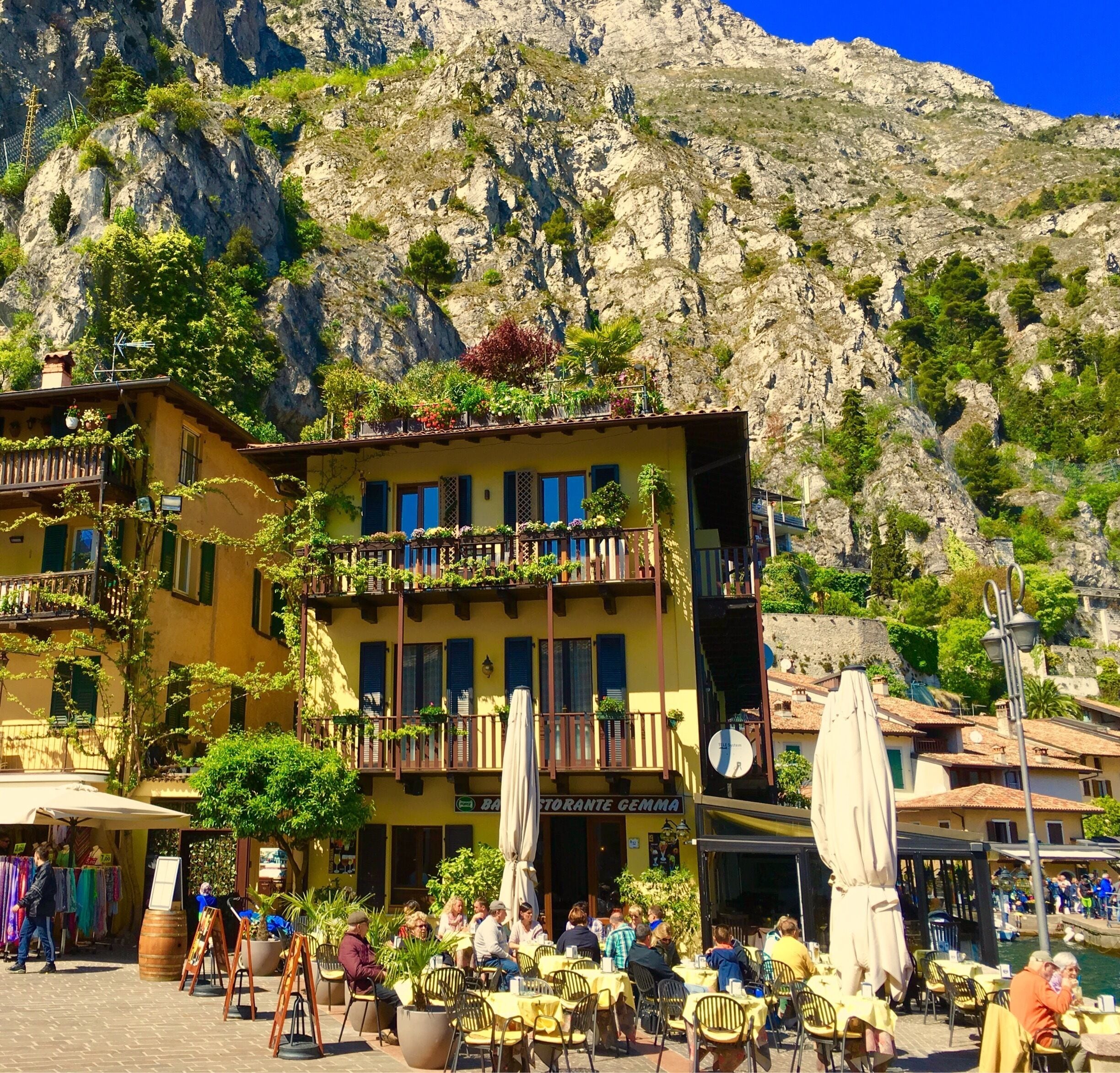 A yellow building with balconies, outdoor seating, and a mountain backdrop.