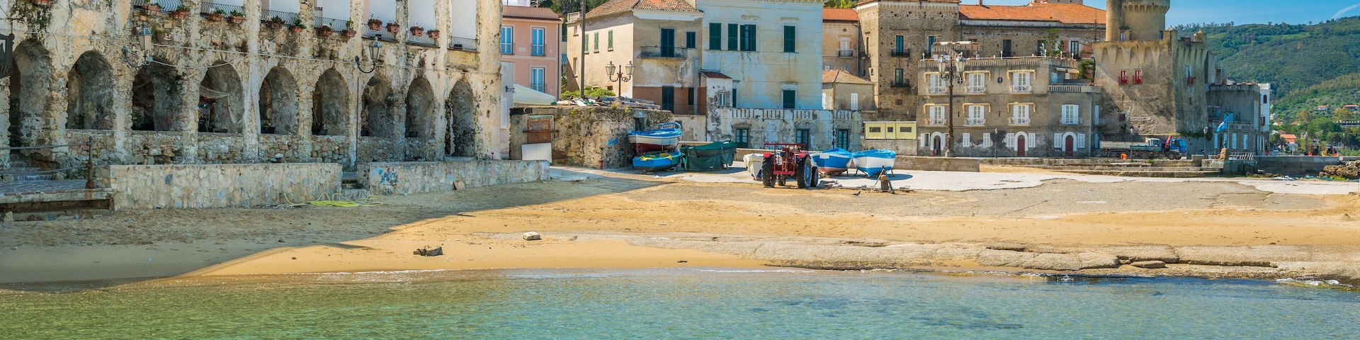 A coastal town with clear waters, historic buildings, and a sandy beach.