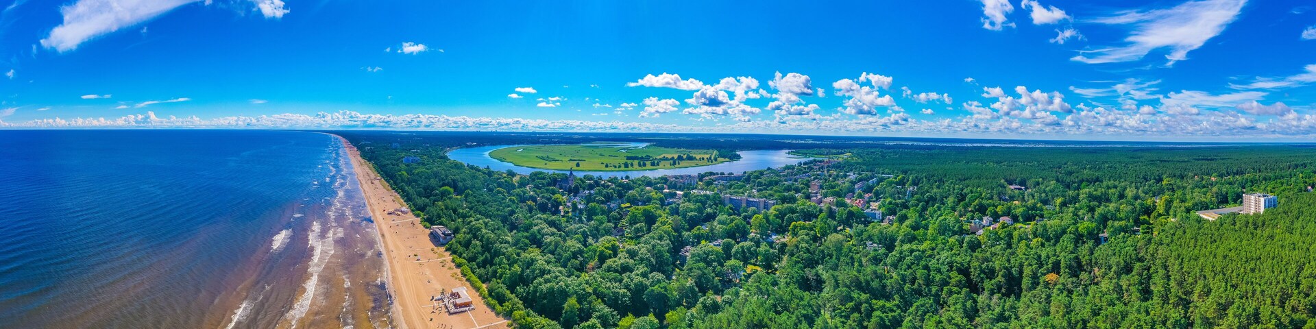 Uma cidade costeira com praia, rio e área arborizada.