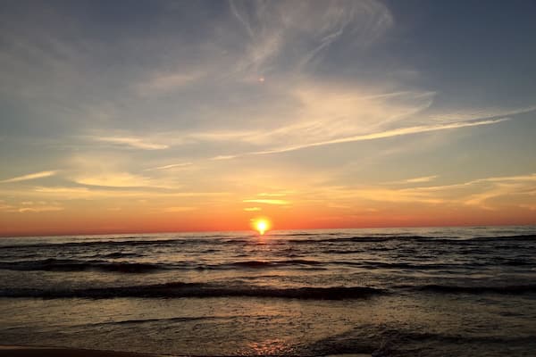 Ein Sonnenuntergang über dem Meer mit Wellen und wolkenlosem Himmel.