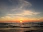 A sunset over the ocean with waves and a clear sky.