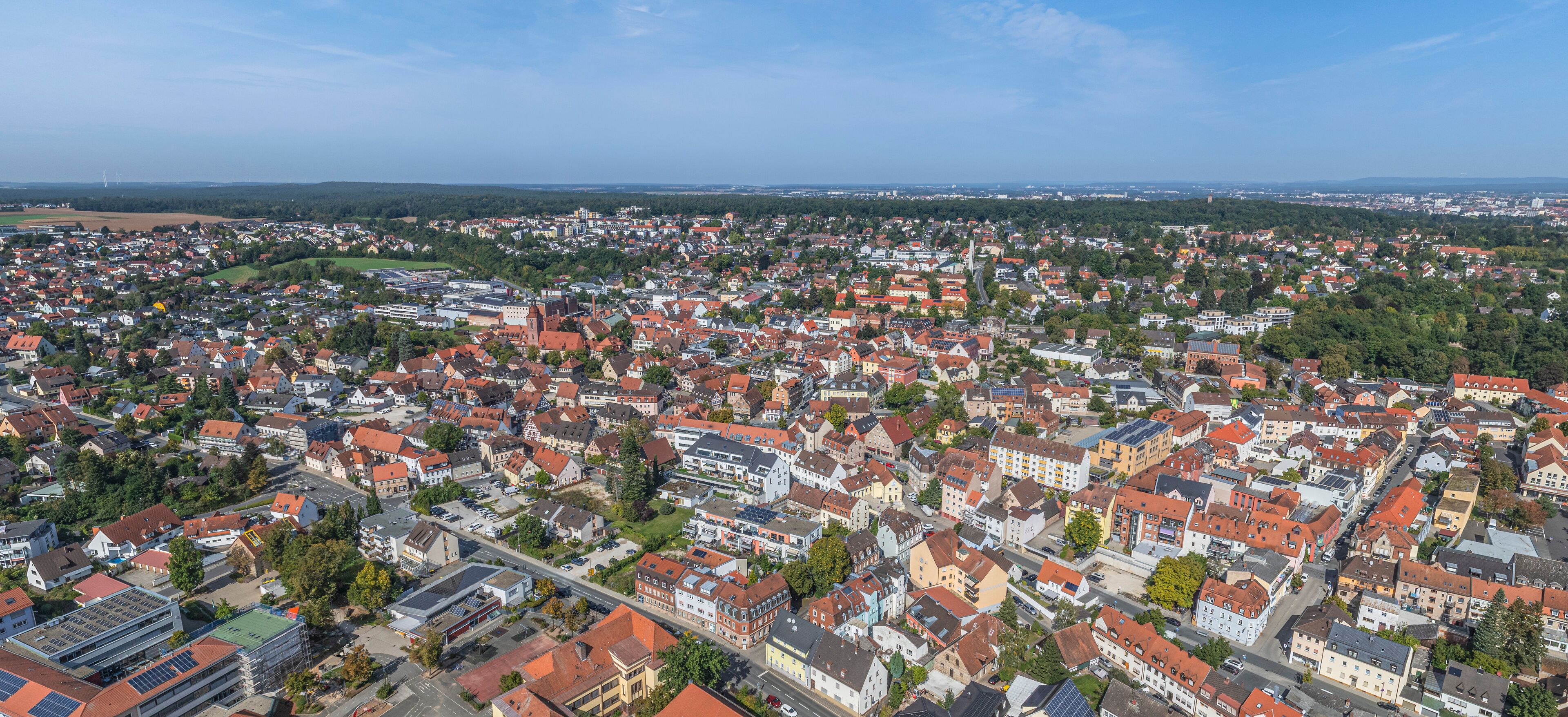 An aerial view of a densely populated town with red-roofed houses, a prominent church, and green spaces.