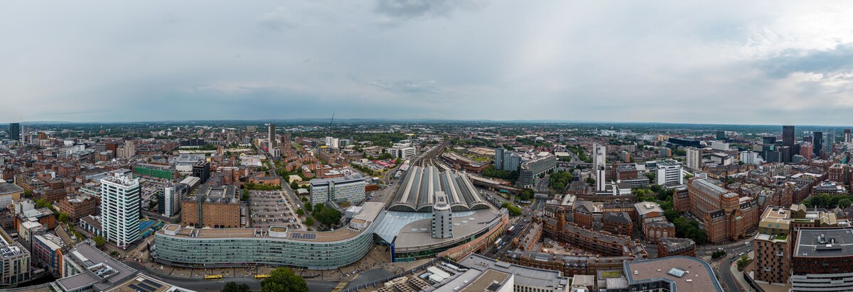 A panoramic view of a cityscape with a prominent curved building, a large stadium, and dense urban architecture.