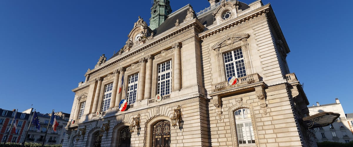 A historic building with ornate architecture, large windows, and flags.