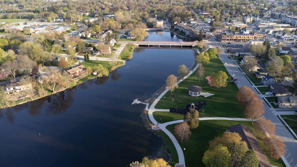 An aerial view of a river with a bridge, surrounded by residential areas and greenery.