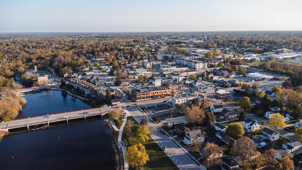 An aerial view of a town with a river, a bridge, and various buildings.
