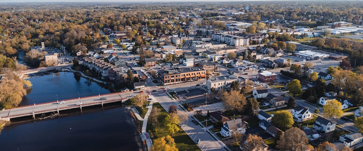 An aerial view of a town with a river, a bridge, and various buildings.