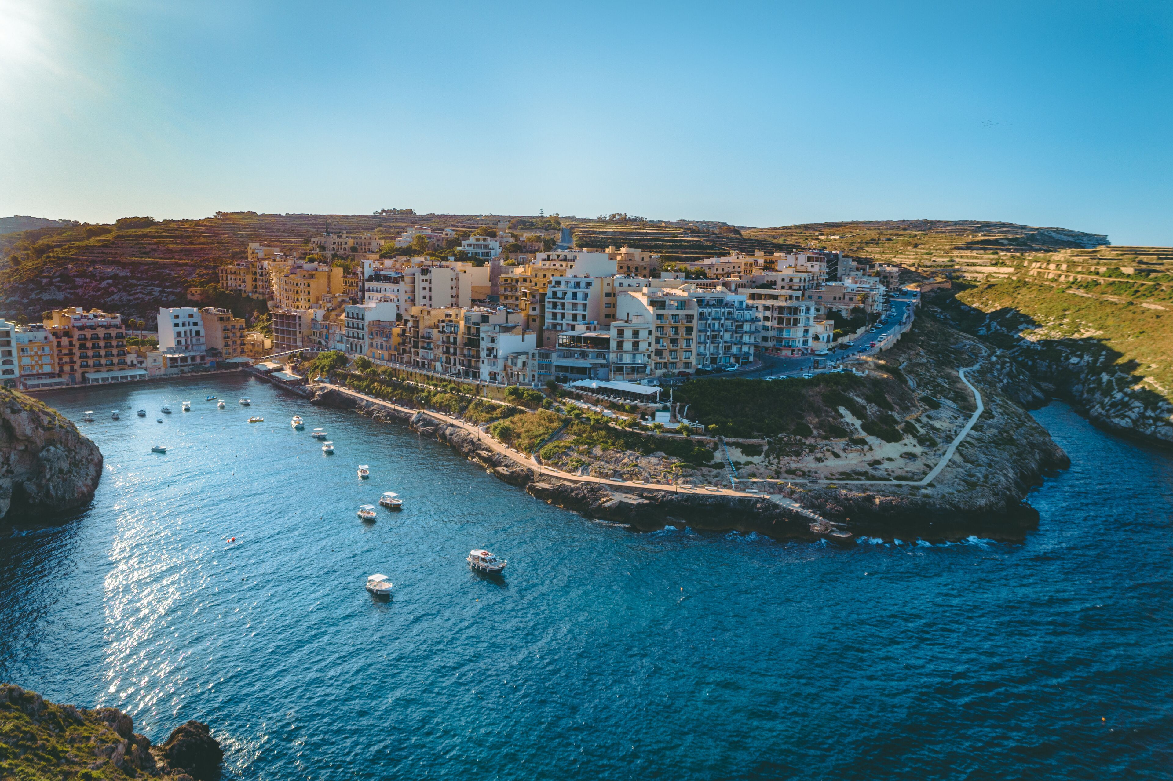 A coastal town with buildings along the waterfront, boats in the water, and a rocky coastline.