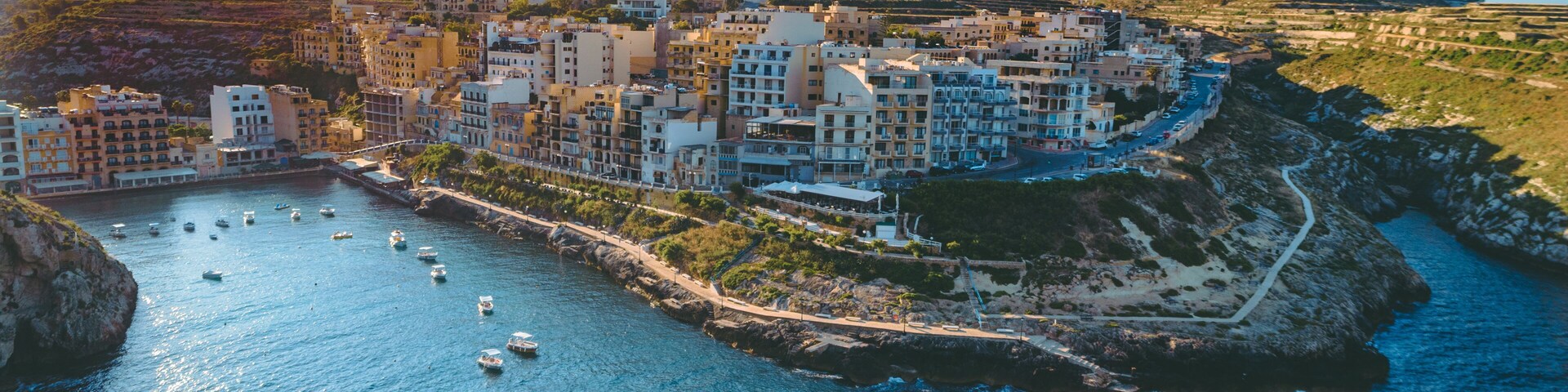 A coastal town with buildings along the waterfront, boats in the water, and a rocky coastline.