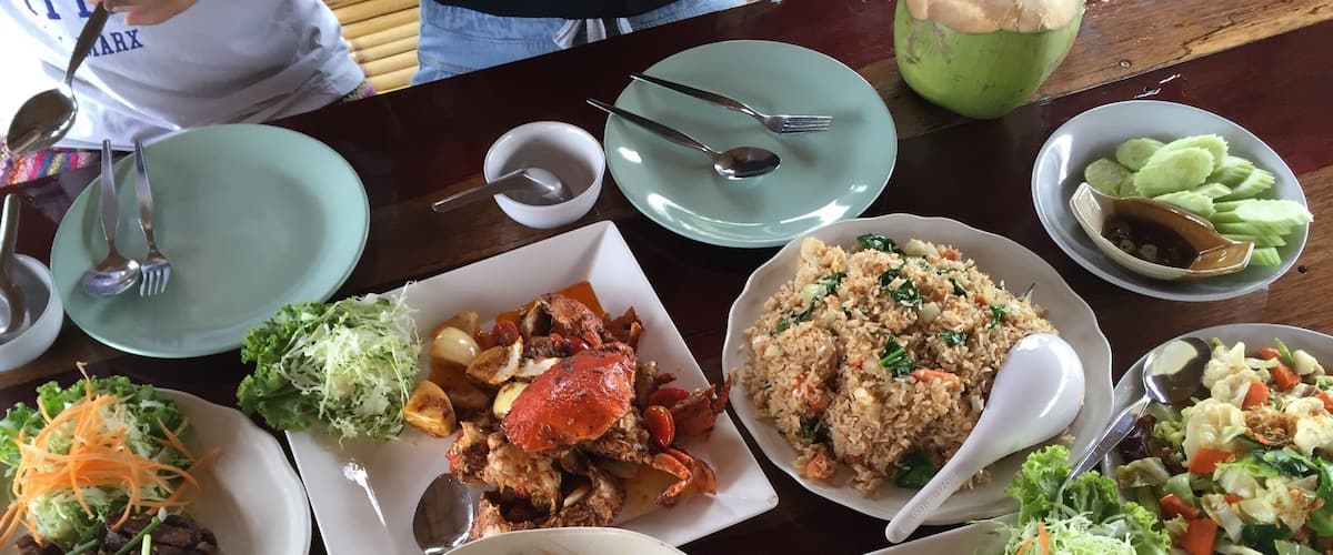 A variety of dishes including seafood, rice, and salads on a wooden table.