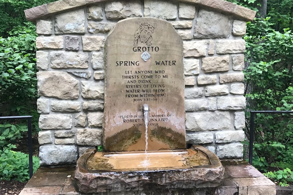 A stone monument with a spring, surrounded by greenery.