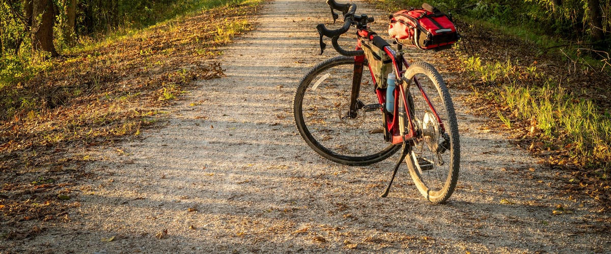 A mountain bike parked on a dirt path surrounded by trees.