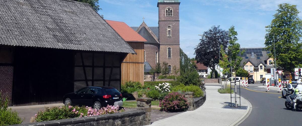 A church with a tall steeple and a brick building with a sloped roof.