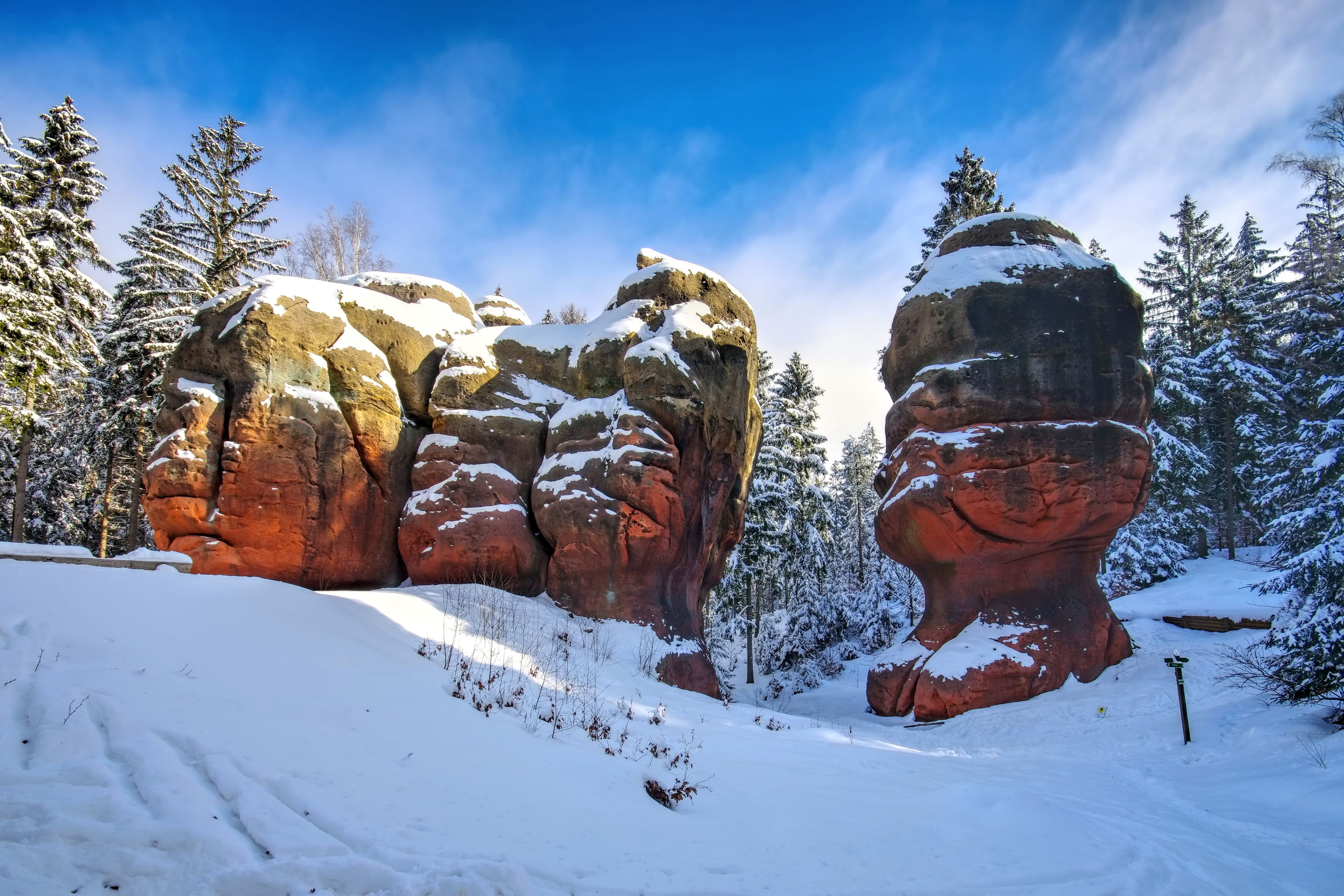 A snow-covered landscape with large rock formations and evergreen trees.
