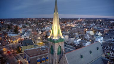 Un paisaje urbano al anochecer, con una imponente aguja de iglesia iluminada contra un cielo crepuscular.