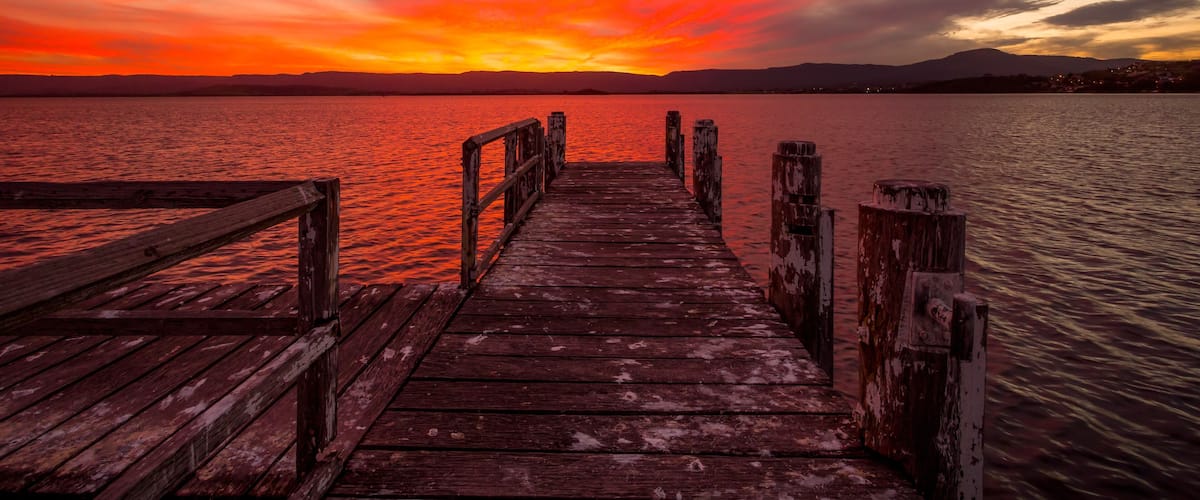 Burning red sunset on the lake with timber jetty