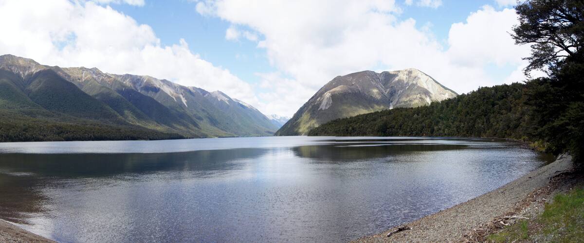 A calm lake surrounded by mountains and a forested area.