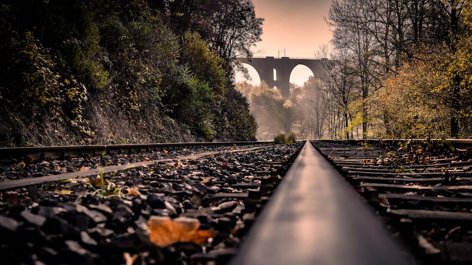 A railway track with a bridge in the background.