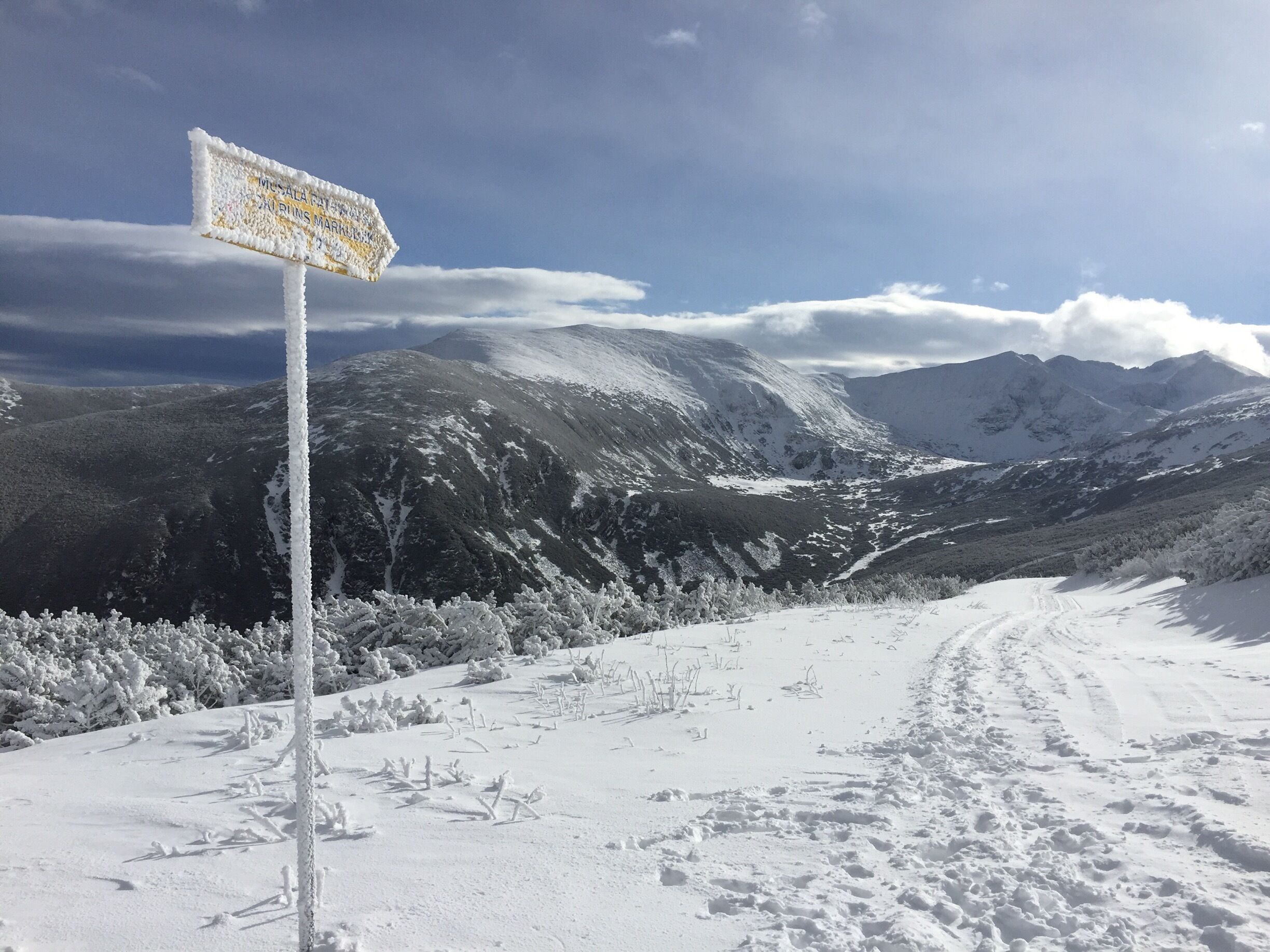 A snow-covered mountain landscape with a signpost indicating directions.
