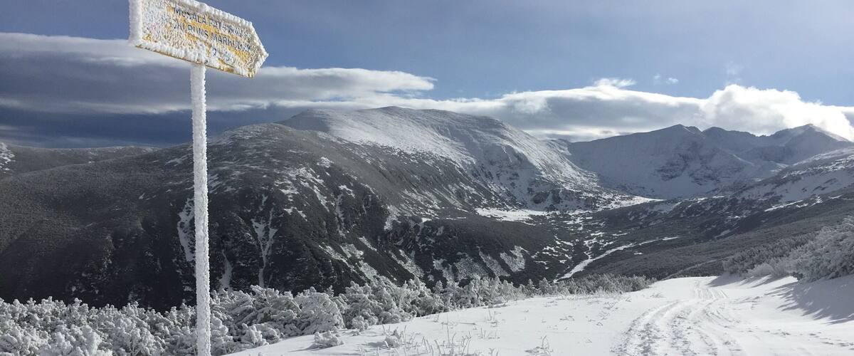 A snow-covered mountain landscape with a signpost indicating directions.