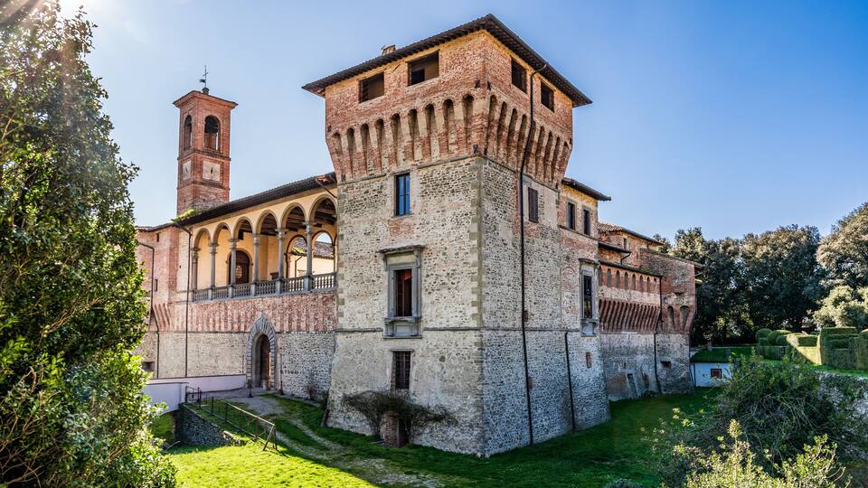 A historic building with a bell tower, arched windows, and a well-maintained garden.